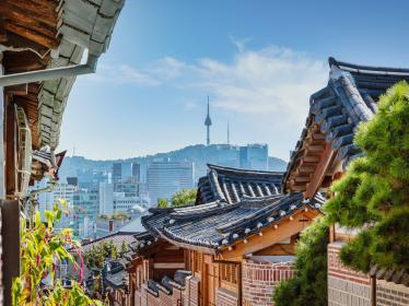 View down a street in Bukchon Hanok Village with Seoul skyline in the background