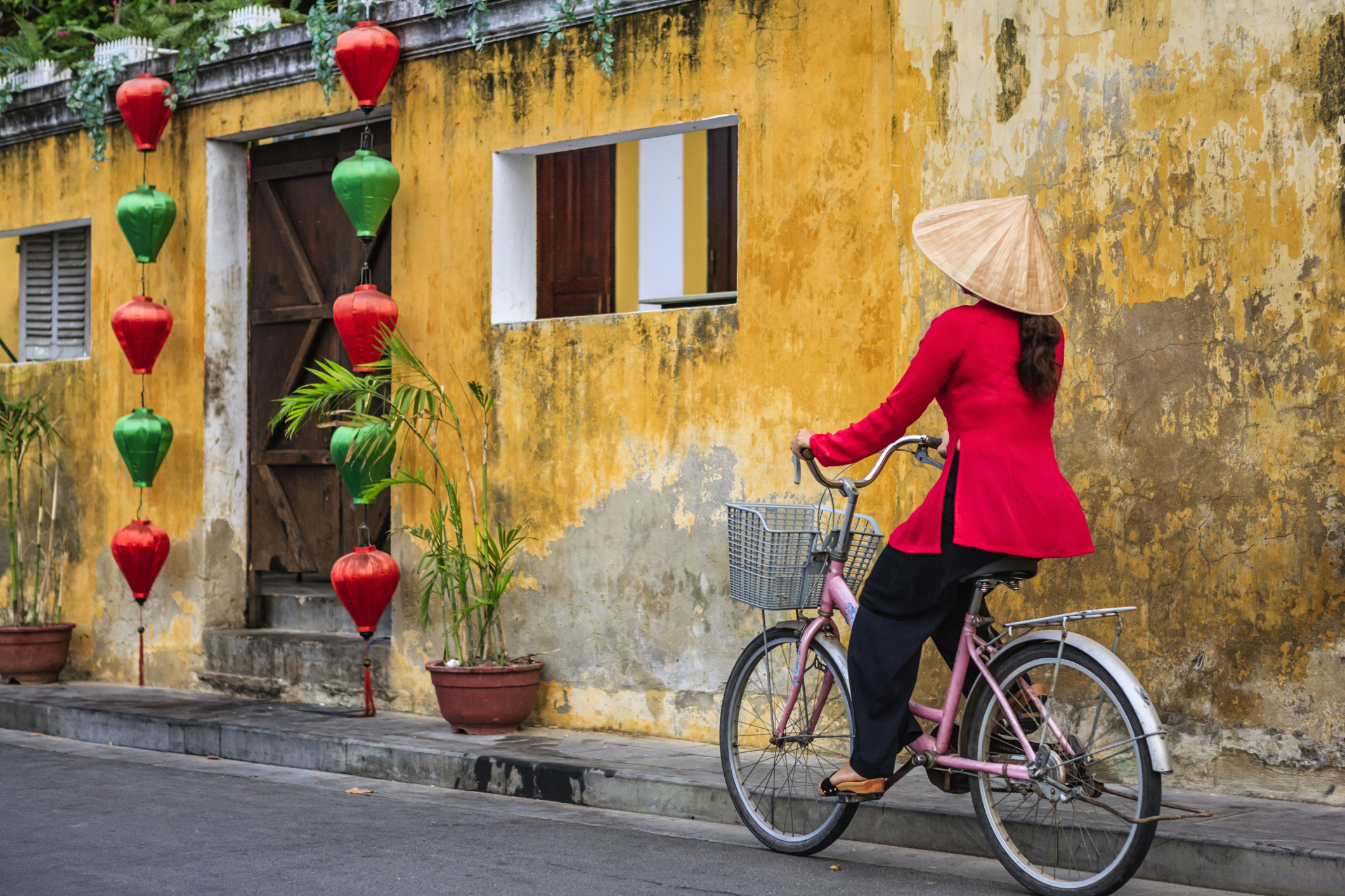 Vietnamese woman riding a bicycle, old town in Hoi An city, Vietnam