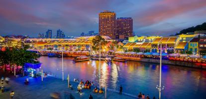 The night lights with vibrant colors in Singapore's Clarke Quay area, with passersby enjoying the riverside walk