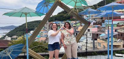 Two friends pose together in front of Gamcheong Village in Busan, South Korea