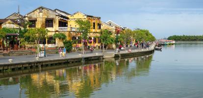 Tourists walk in Hoi An's riverside promenade during the day in Vietnam
