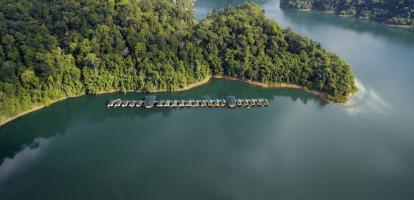 Overwater bungalows next to lush outcrop of land in Khao Sok National Park