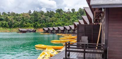 Overwater bungalows with kayaks next to lush outcrop of land in Khao Sok National Park