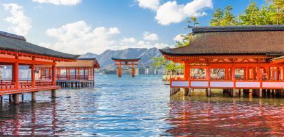 View across the water towards Miyajima's red floating torii gate, with Itsukushima shrine visible in the foreground