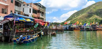 Fishing boats docked up by covered jetties alongside colorful houses in Tai O Village in Hong Kong's Lantau Island