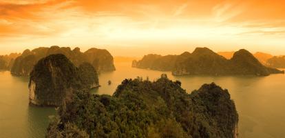 Sun sets over the dramatic limestone karst formations of Halong Bay in Vietnam