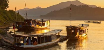 Three moored boats rest during sunset in the Mekong section of Luang Prabang, in Laos