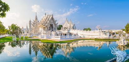 Soft sunset colors illuminate the white temple in Chiang Rai, with beautiful reflection on the pond in the temple grounds