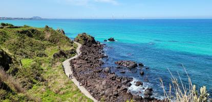 Hikers walk along the Handam Coast trail surrounded by azure waters in Jeju island