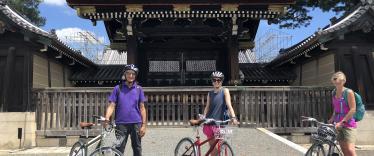 Three cyclists pausing for a photograph outside shrine