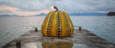 Yellow and black pumpkin sculpture on pier at Naoshima Island