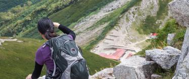 Hiker rests sat down on a rock ledge while staring at the mountainous scenery around the Kamikochi area