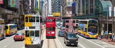 Trams and buses running alongside each other on street in Hong Kong
