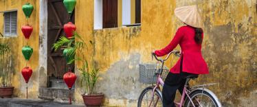 Vietnamese woman riding a bicycle, old town in Hoi An city, Vietnam