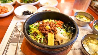 A colourful bowl of Korean bibimbap surrounded by side dishes