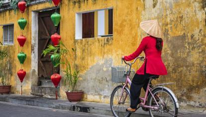 Vietnamese woman riding a bicycle, old town in Hoi An city, Vietnam