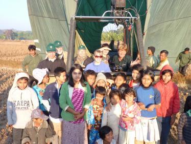 Local people standing in front of a hot air balloon in Burma
