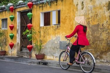 Vietnamese woman riding a bicycle, old town in Hoi An city, Vietnam